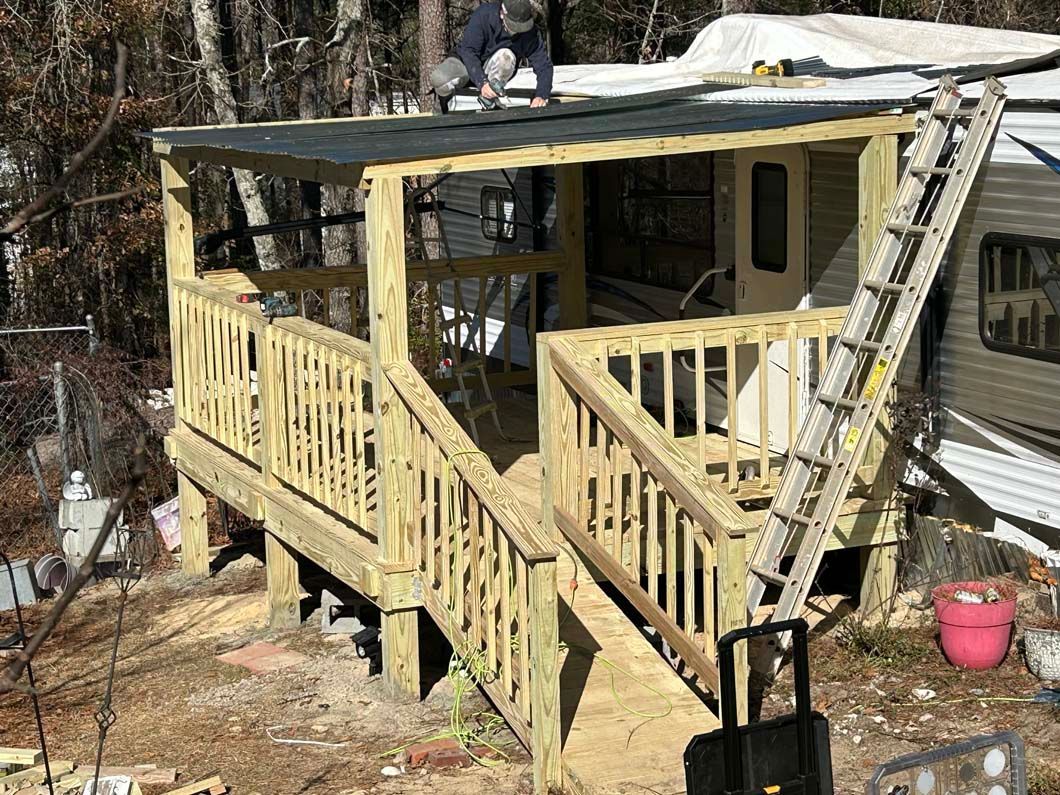 A man is working on a wooden deck next to a trailer.