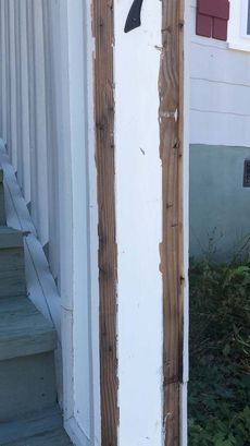 A white house with a wooden post in the middle of it.