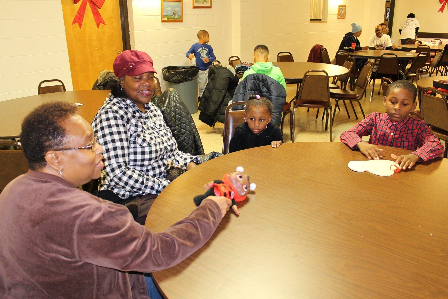 People seated around a table in a community room, talking and holding small objects