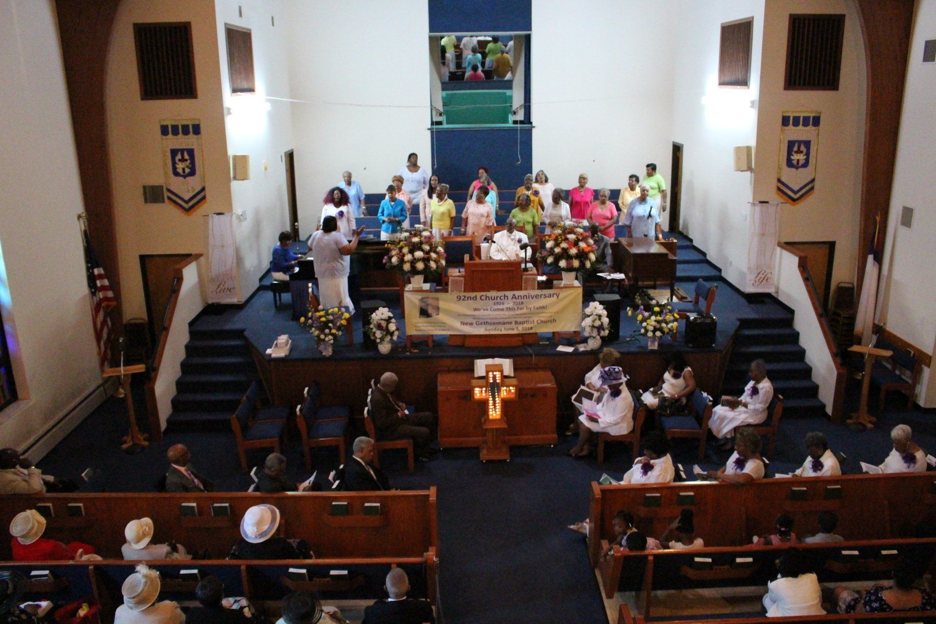 Church congregation gathered around the altar during a service, with pews and stained glass visible.