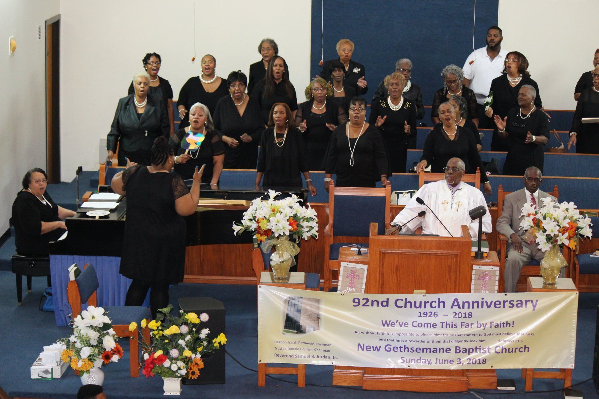 Choir performing in a church sanctuary beside a banner reading “52nd Church Anniversary”