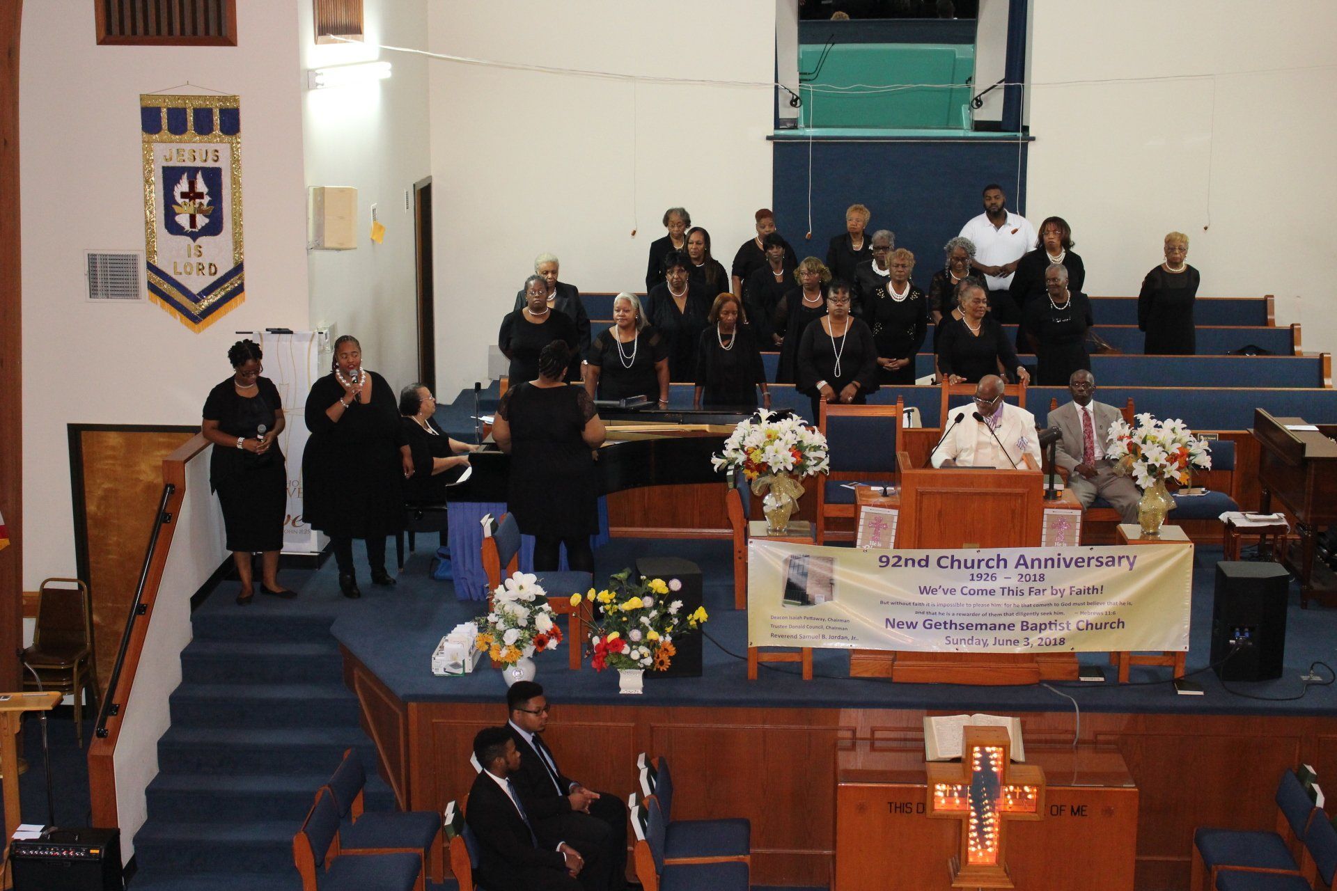Church sanctuary with people on a stage and seated choir during a formal service
