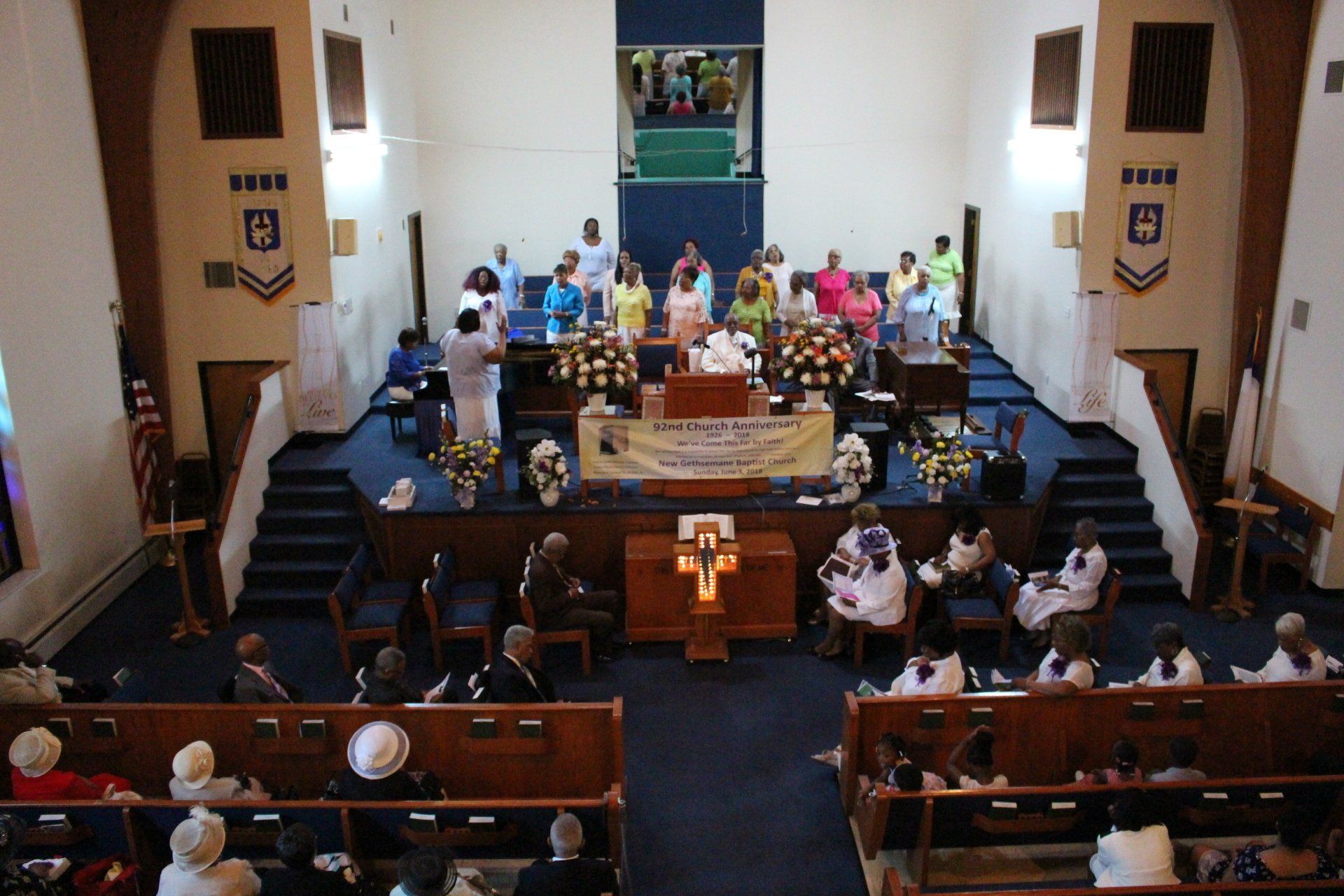 Church congregation gathered for a service, with people seated in pews facing the altar.