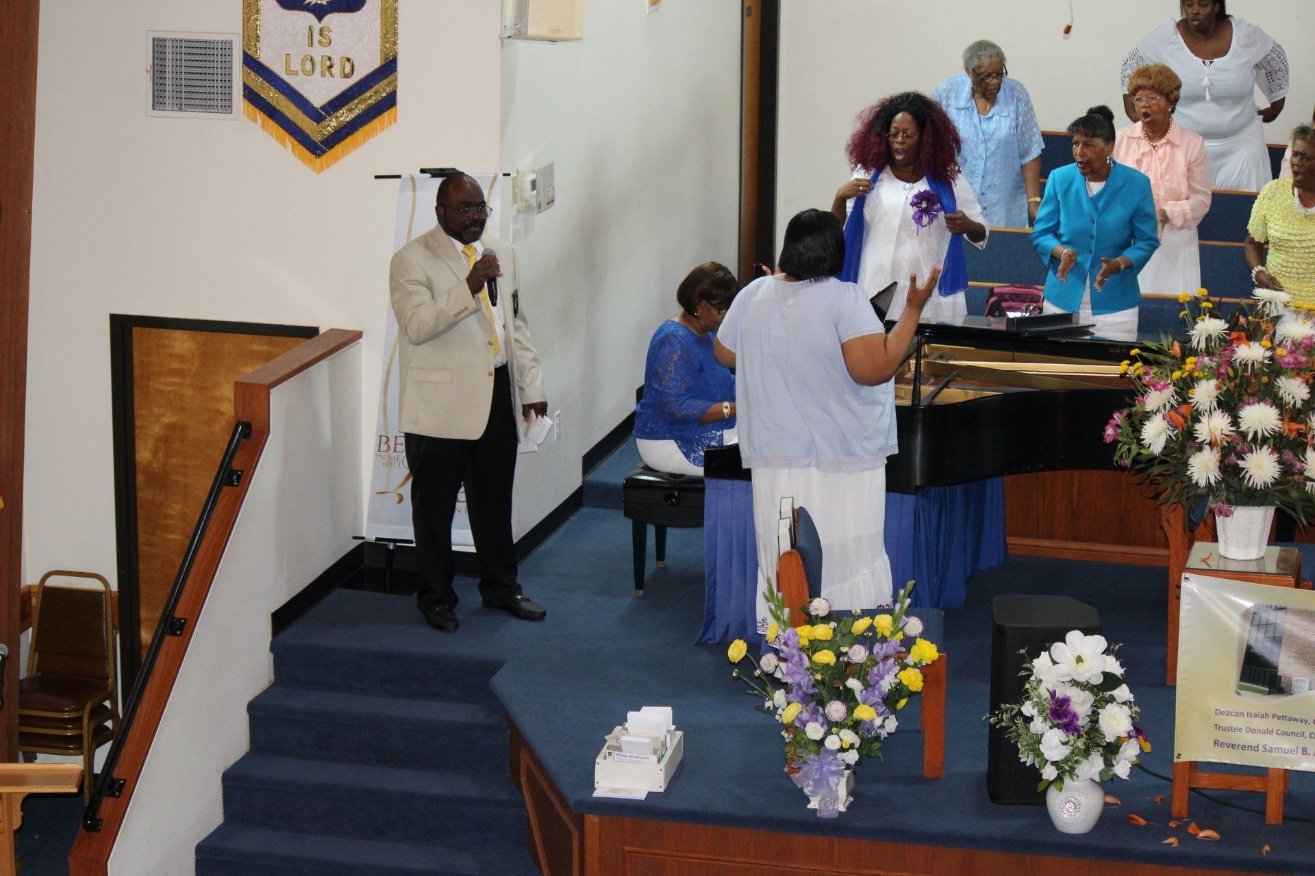 People gathered on a church stage, with flowers and a podium during a service