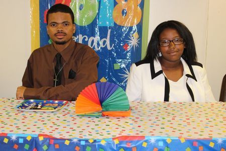 Two people seated behind a polka-dot table with a colorful paper fan centerpiece at an event table