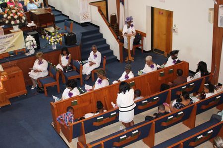 People seated in a church sanctuary during a service, facing the front pews and pulpit area.