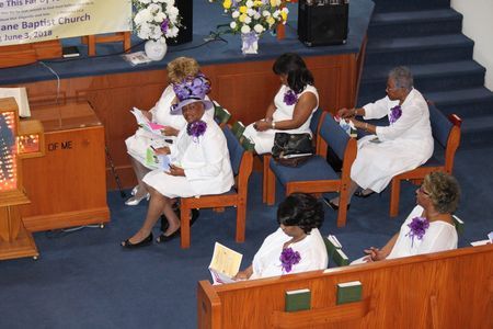 People seated in a church sanctuary, reading programs during a service