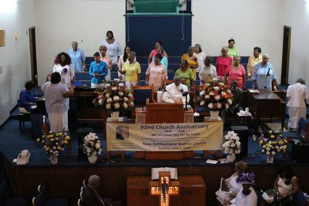 Church choir on stage with singers and floral arrangements during a celebration service