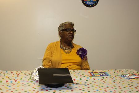 Person in a yellow cardigan sits at a confetti-covered table, looking to the side.