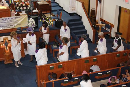 Congregants in white robes processing down church aisle during a service