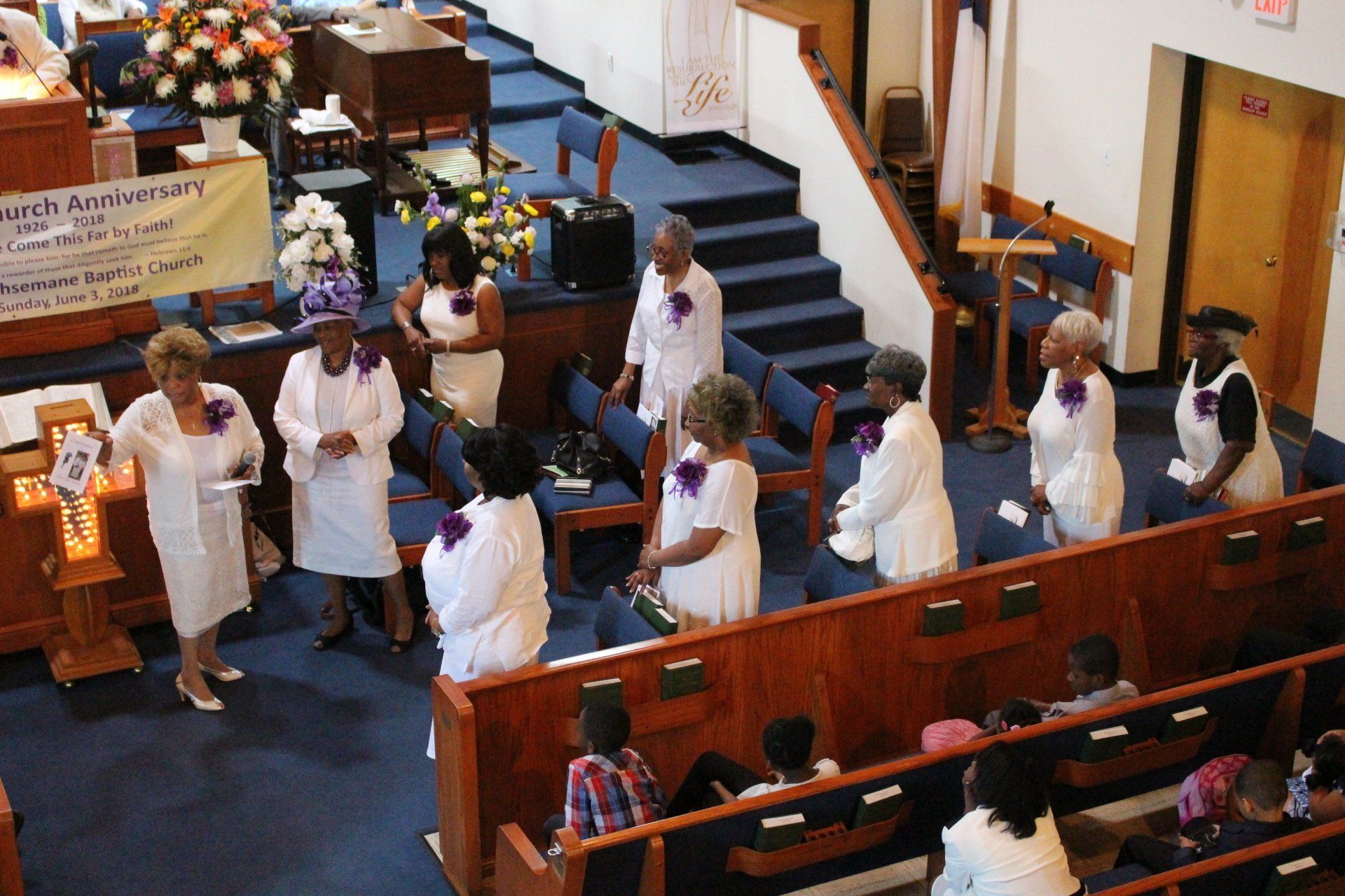 Church procession with people in white robes moving along the front pews