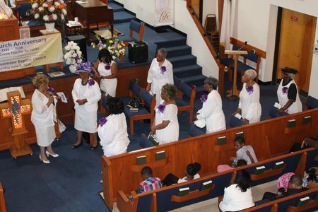 People in white robes gathered in a church aisle during a service