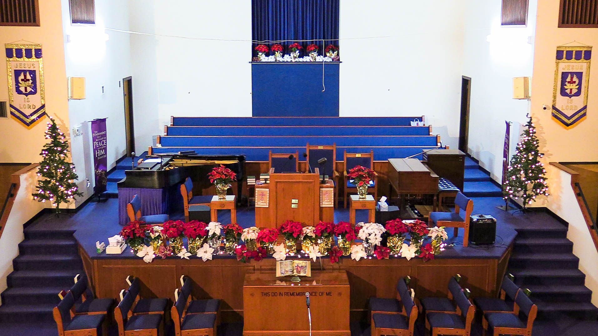 Church sanctuary with blue pews and a decorated stage for a holiday service