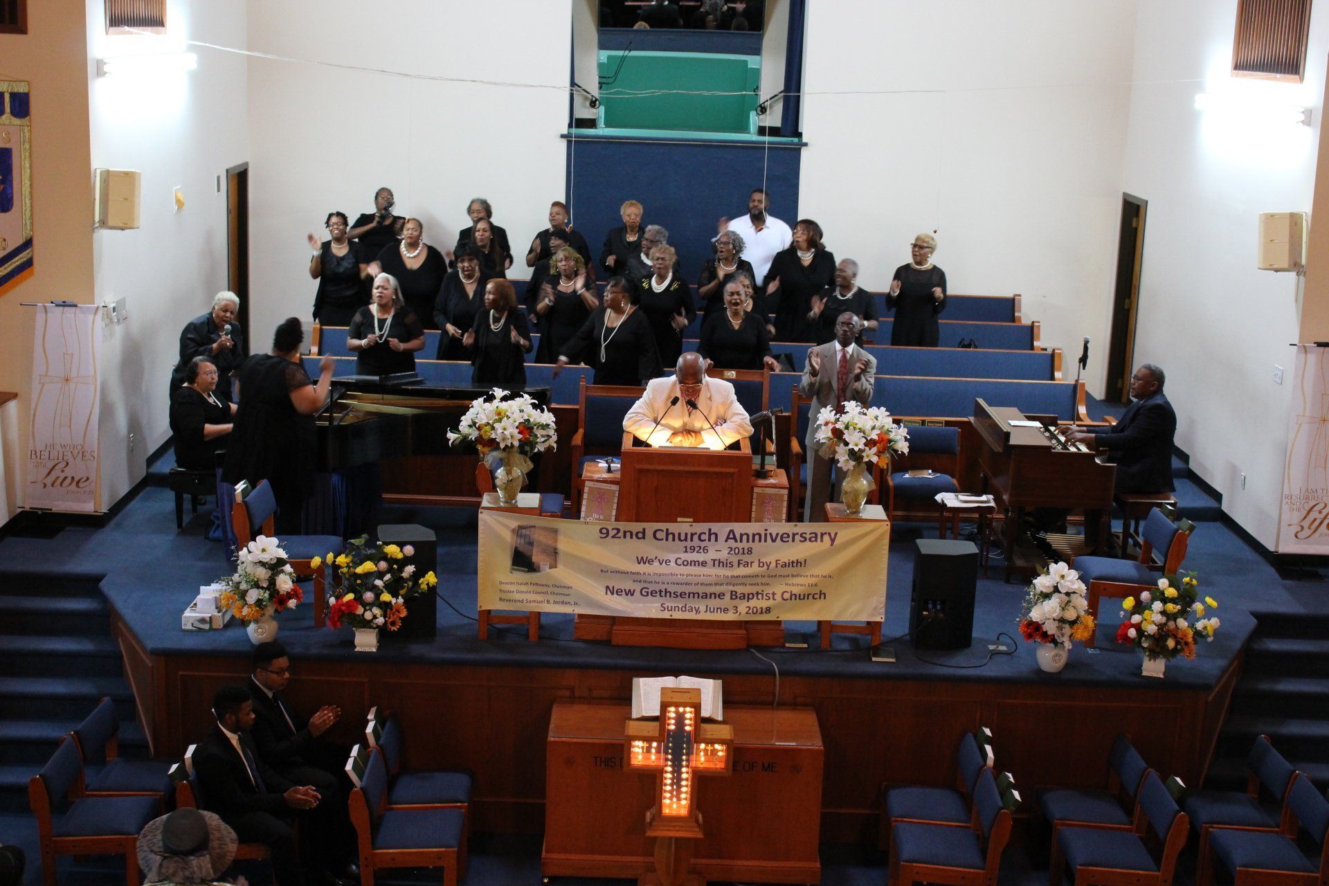 Church service with people seated on pews and a decorated altar at the front of the sanctuary.