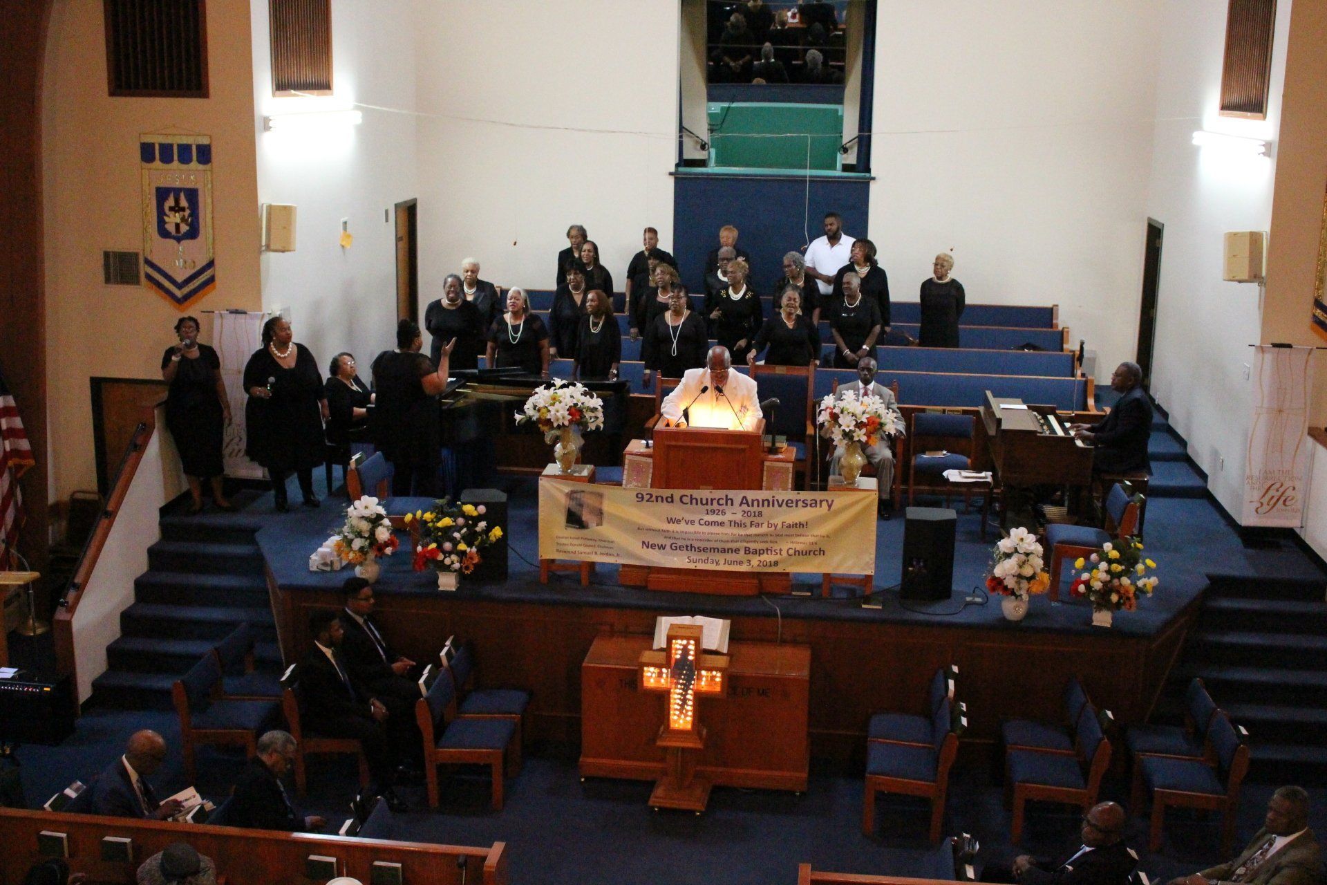 Church sanctuary with choir and congregation seated around a central altar, viewed from the back.