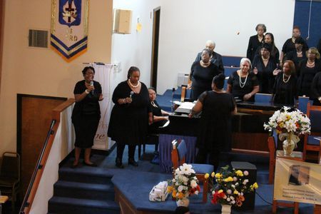 Choir singing in a church sanctuary near a podium and floral arrangements