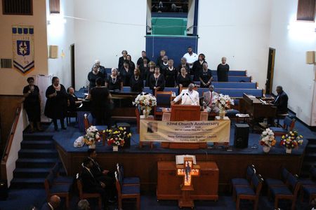 Church sanctuary with people seated on the stage and a floral display near the altar