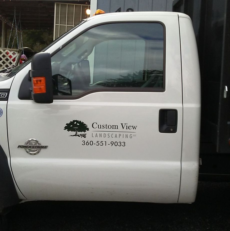 White custom landscaping truck side door with company logo and phone number.