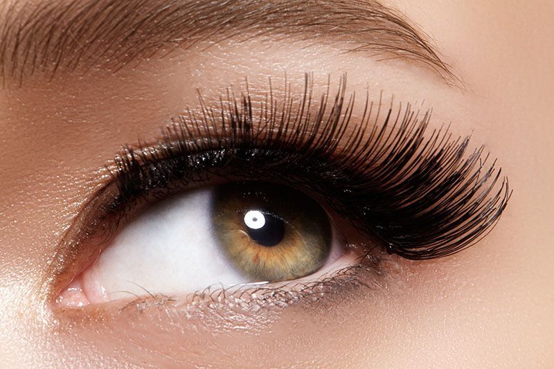 A close up of a woman 's eye with long eyelashes.