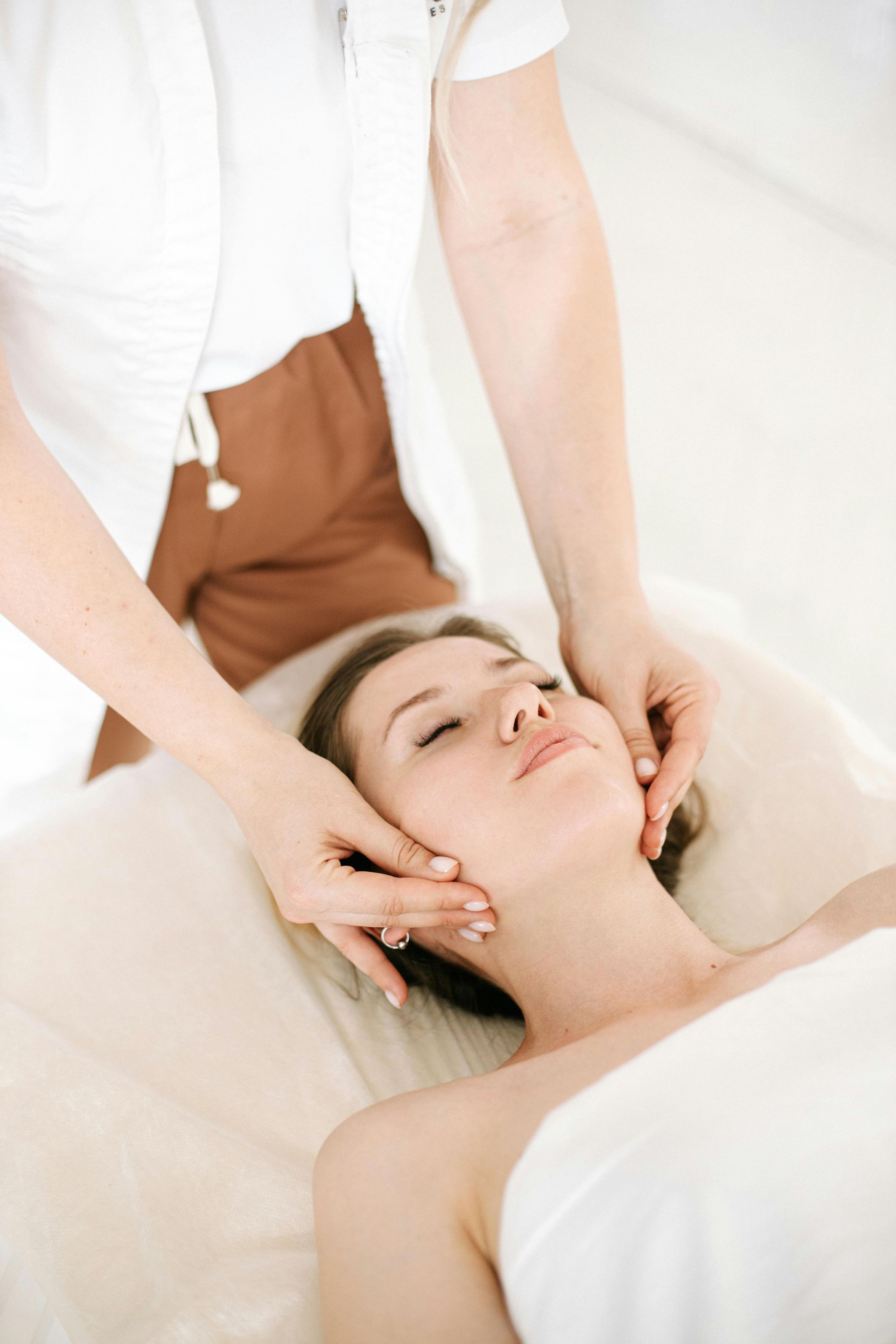A woman is getting a facial massage at a spa.