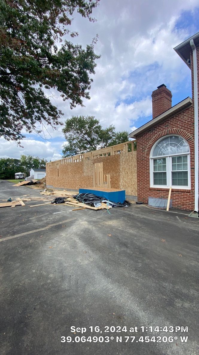 Partially demolished brick building with exposed framing, debris, and a blue tarp on the ground