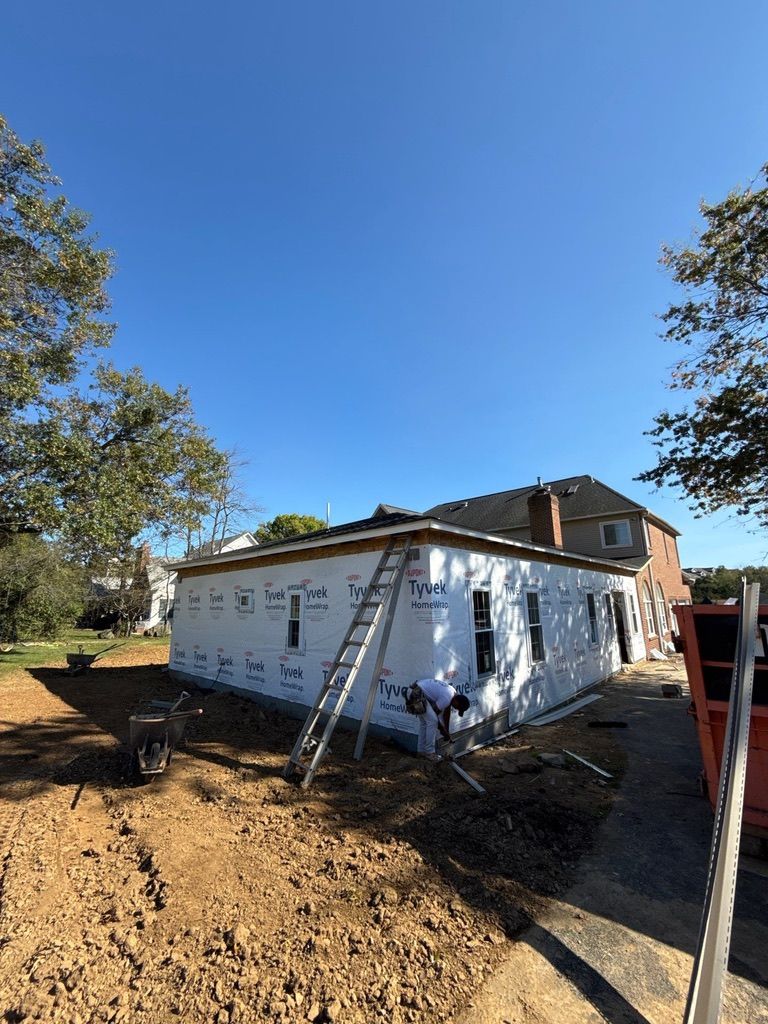 White house under construction with ladder, dirt yard, and clear blue sky