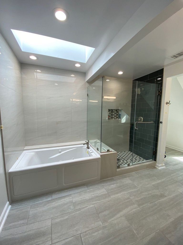 Modern bathroom with soaking tub, glass shower, and gray tile flooring