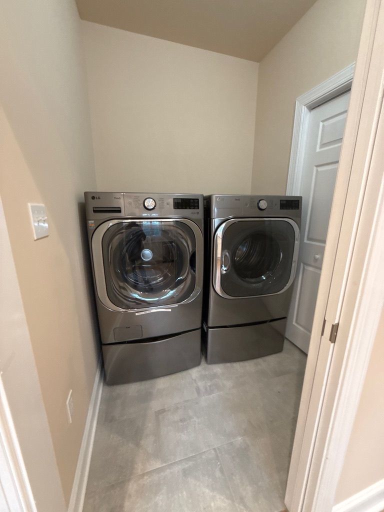 Laundry room with front-loading washer and dryer in a narrow alcove, viewed from the doorway