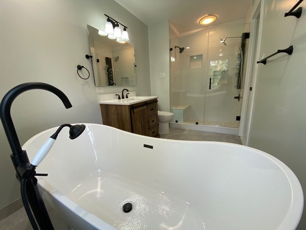 Modern bathroom with freestanding tub, vanity, glass shower, and warm lighting