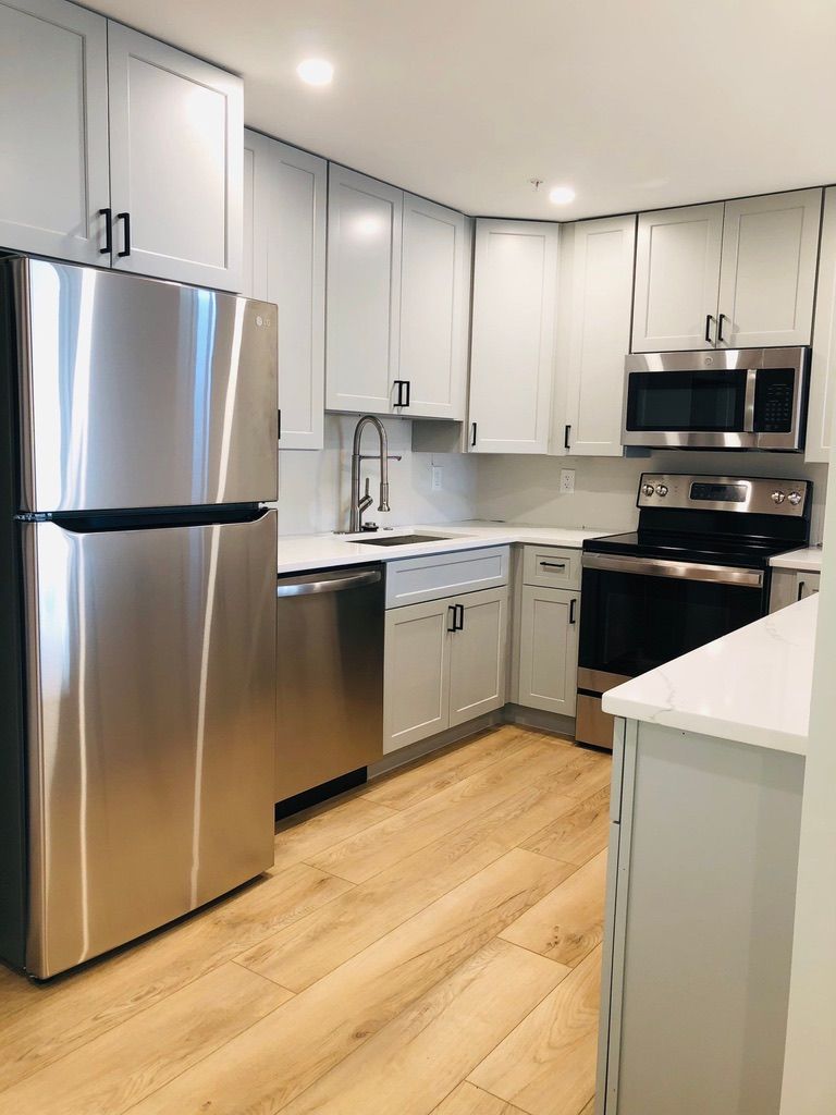 Modern kitchen with stainless steel appliances, white cabinets, and light wood flooring