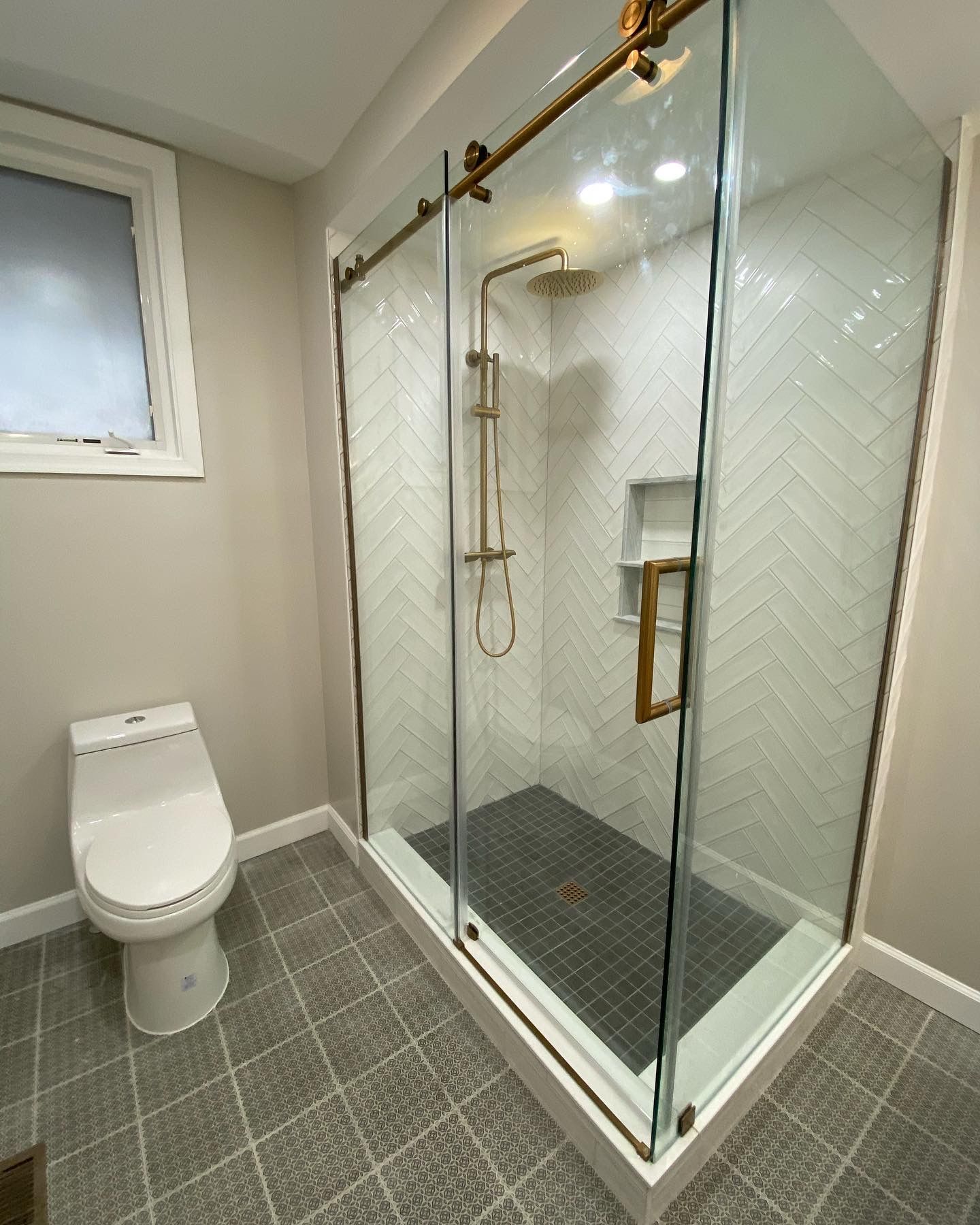 Modern bathroom with toilet and glass-enclosed walk-in shower on gray tile floor