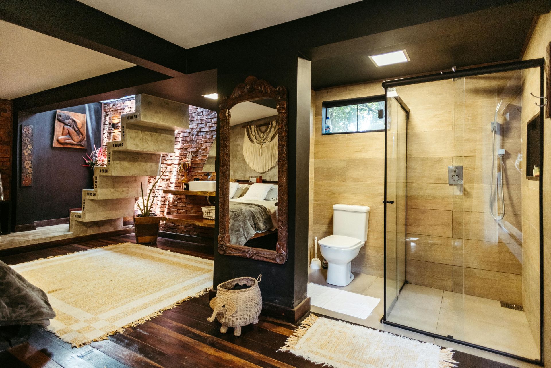 Modern bathroom with glass shower, toilet, staircase, and dark wood accents