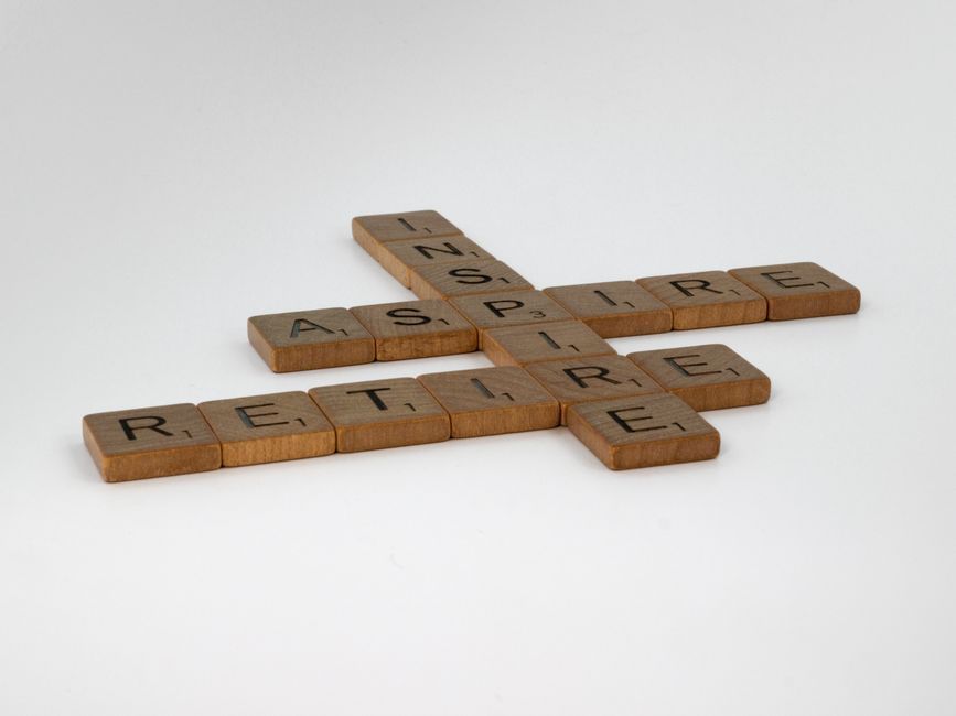 Wooden letter tiles spelling “RETAIL” and “LITTLE” arranged in a crisscross pattern on a white surface