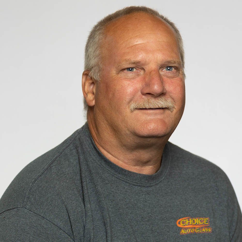 A man with a mustache is wearing a grey shirt with the word choice on it.