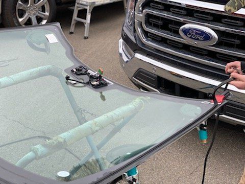 A person is fixing a windshield on a ford truck.