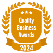 Quality Business Awards 2024 badge: golden shield with laurel, three stars, ribbon.