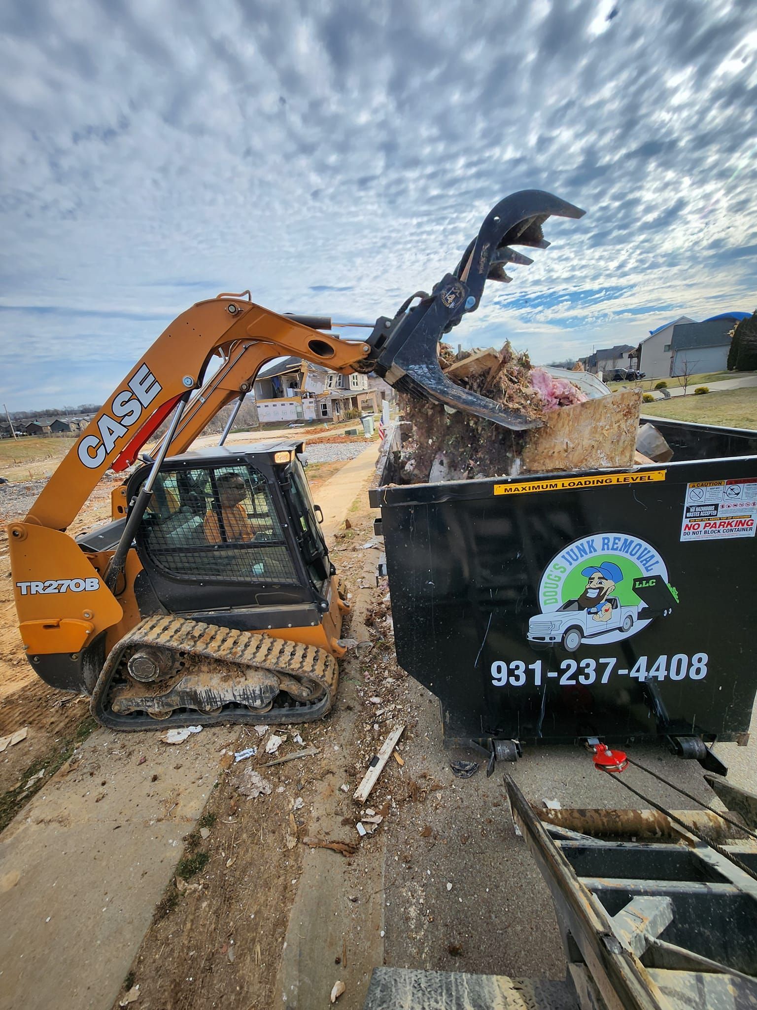 Orange skid steer loading debris into a black dumpster with "Blue Collar Clean Up" logo.
