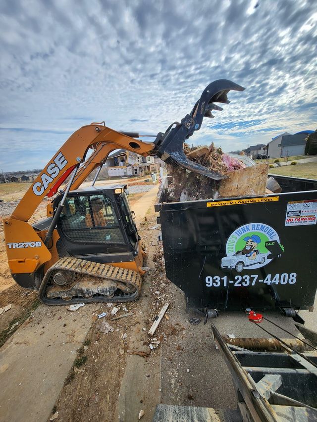 Orange skid steer loading debris into a black dumpster with "Blue Collar Clean Up" logo.