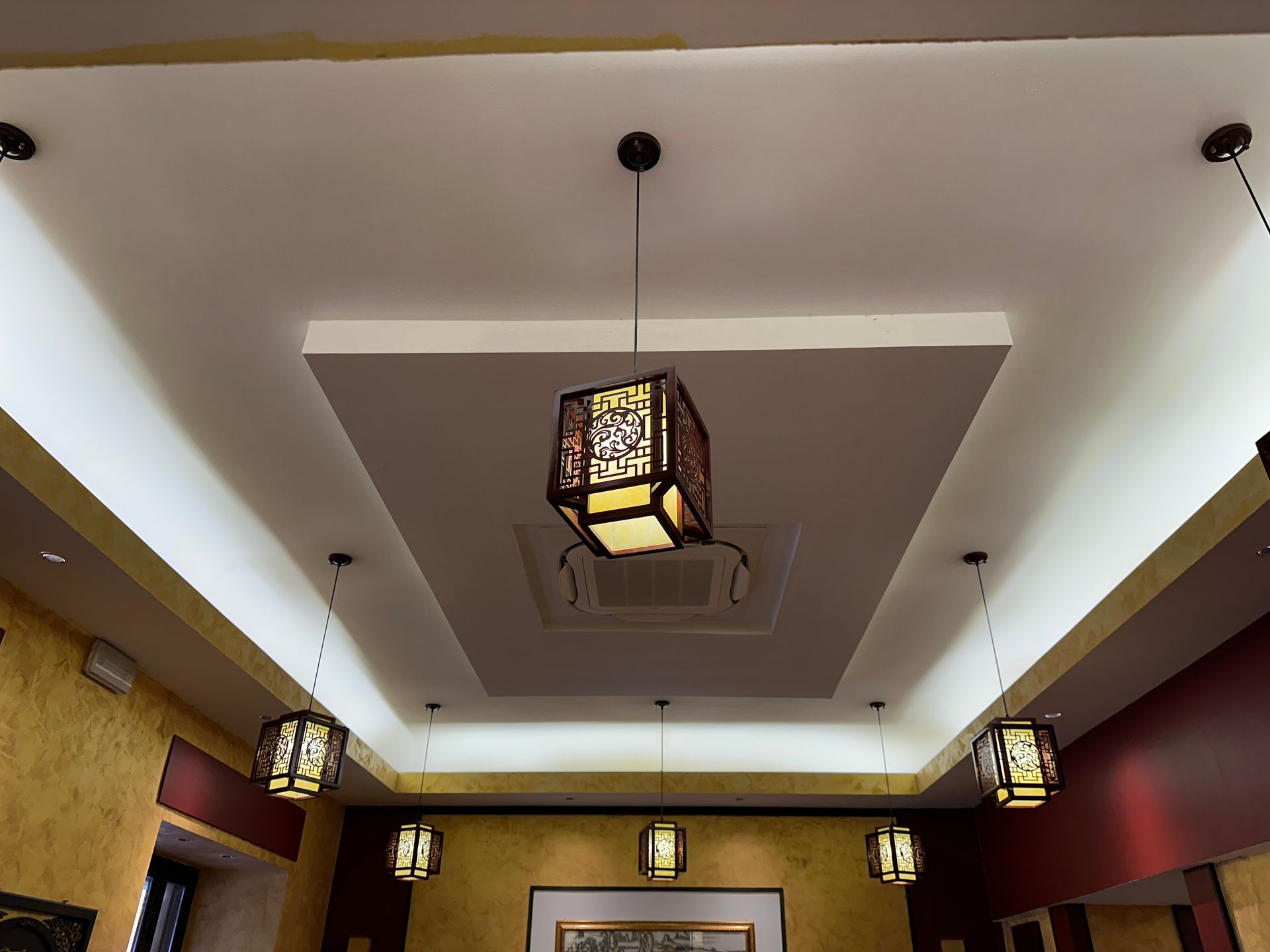 Lanterni a soffitto in un ristorante con faretti incassati e pareti rosse e dorate