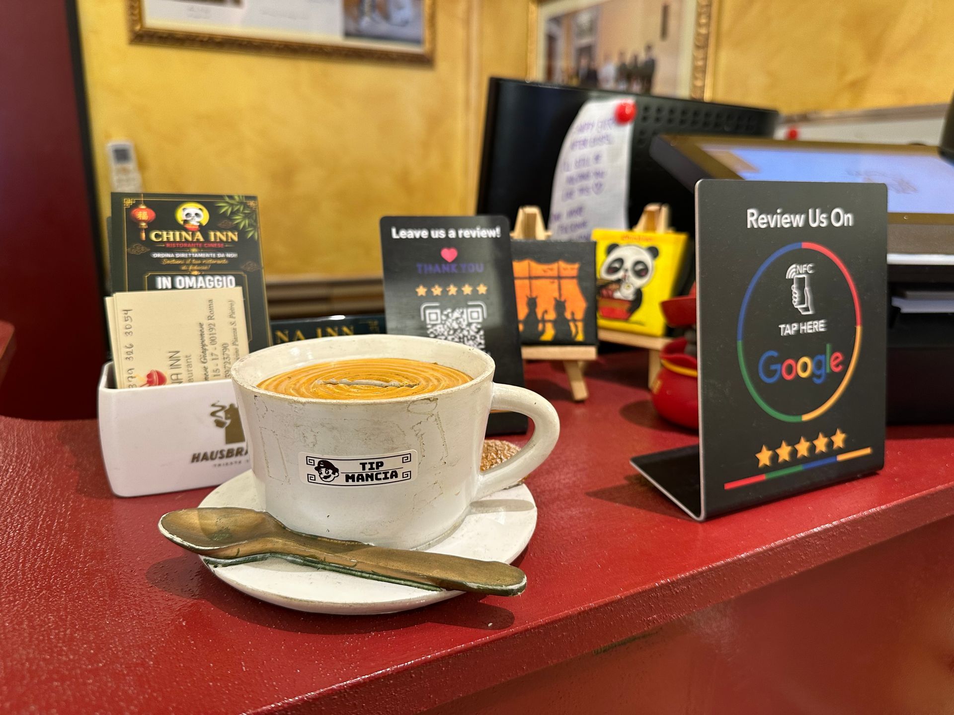 Tazza di caffè su un tavolo rosso con menu e un cucchiaino in un caffè
