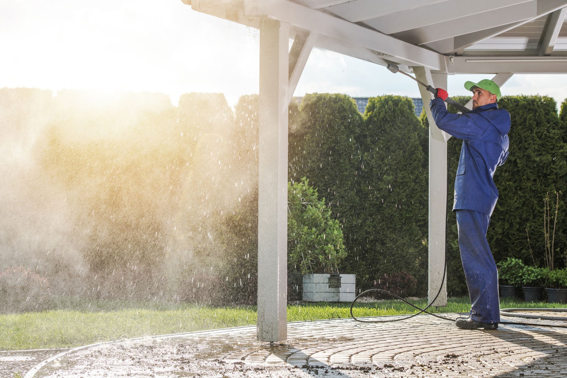 A man is using a high pressure washer to clean a brick sidewalk.
