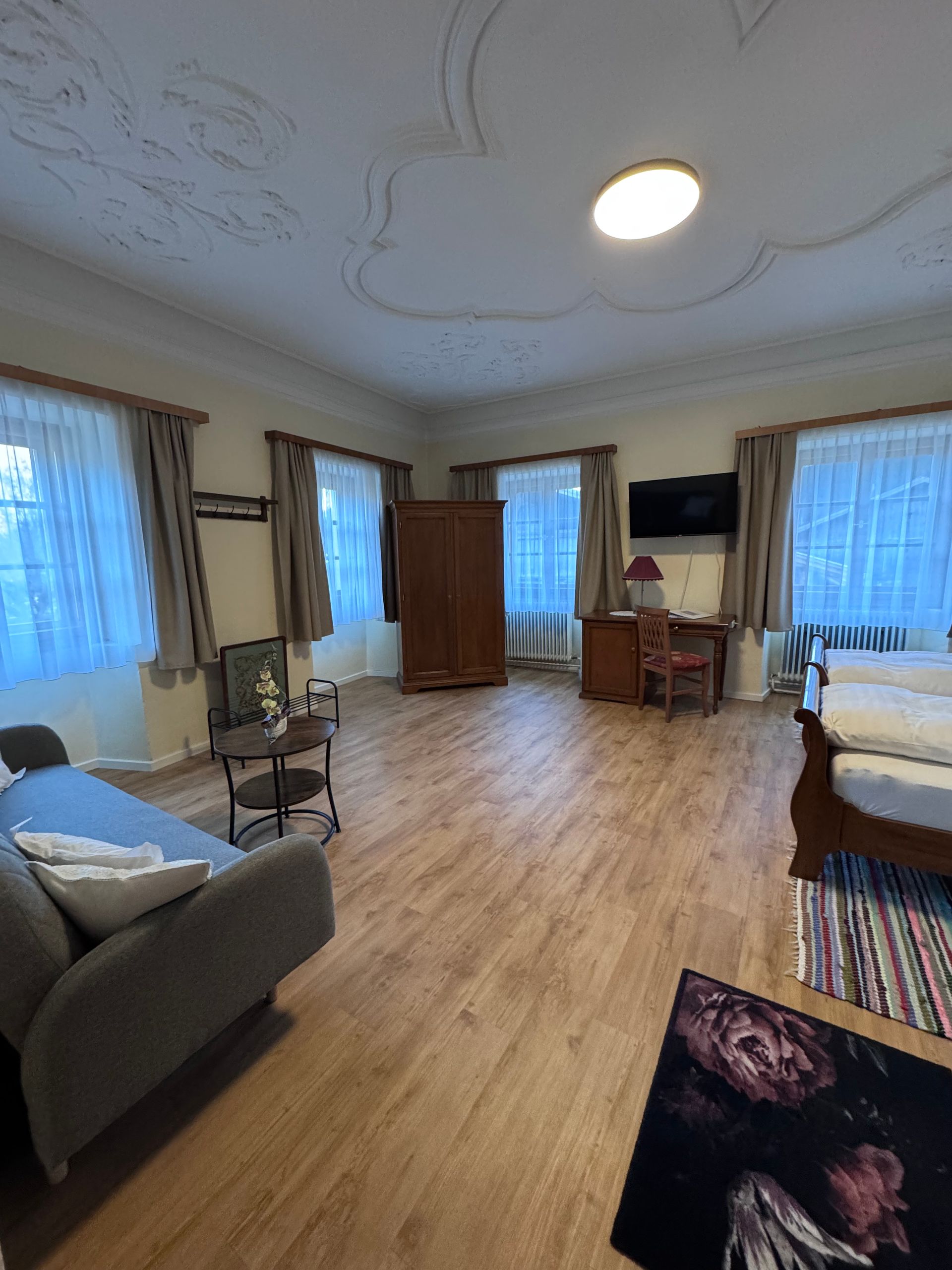 Ein Wohnzimmer mit Couch, Bett, Schreibtisch und Fernseher.