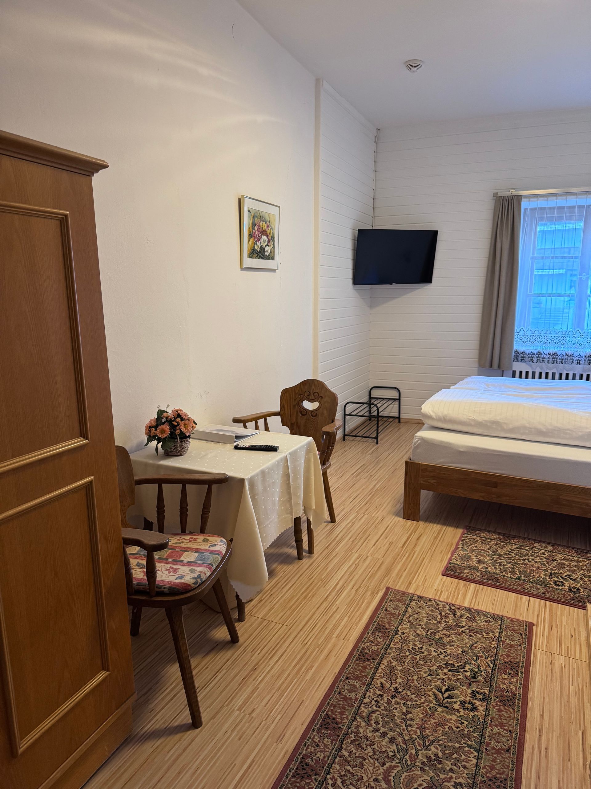 Ein Schlafzimmer mit Bett, Stuhl, Tisch und Fernseher.