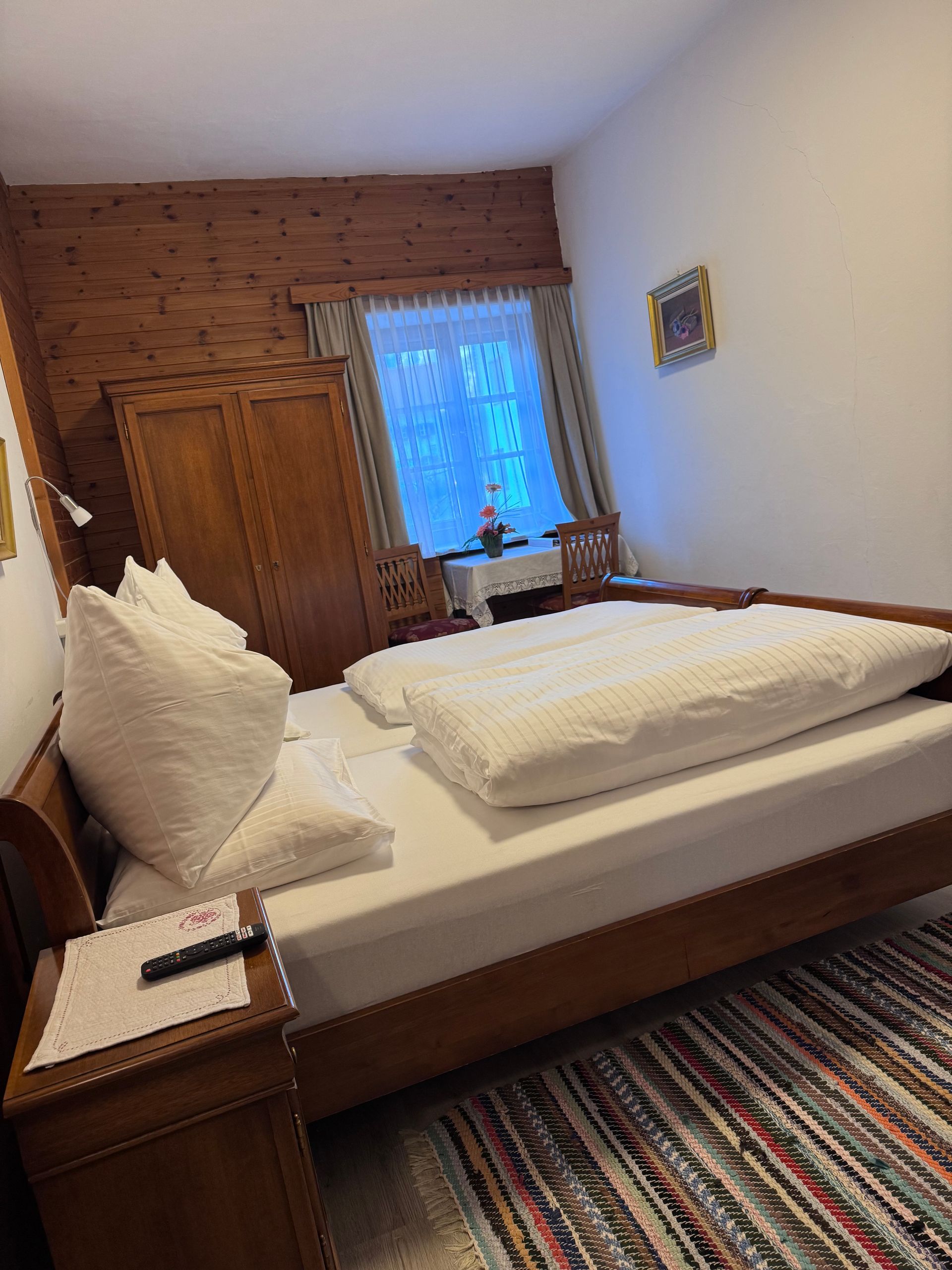 Ein Schlafzimmer mit Bett, Nachttisch, Teppich und Fenster.