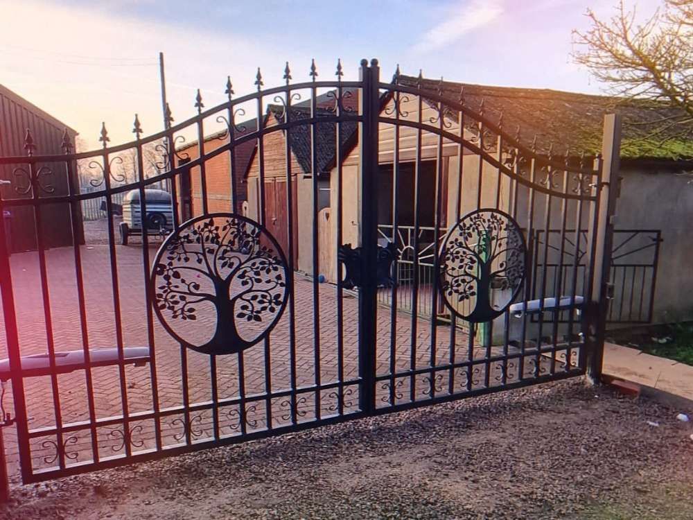 Ornate wrought iron electric gates with circular tree-of-life panels and scrollwork detailing