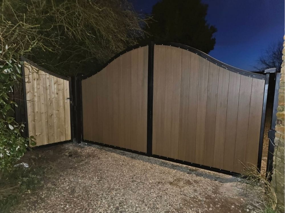 Electric swing gates with a curved top and timber infill in a black metal frame