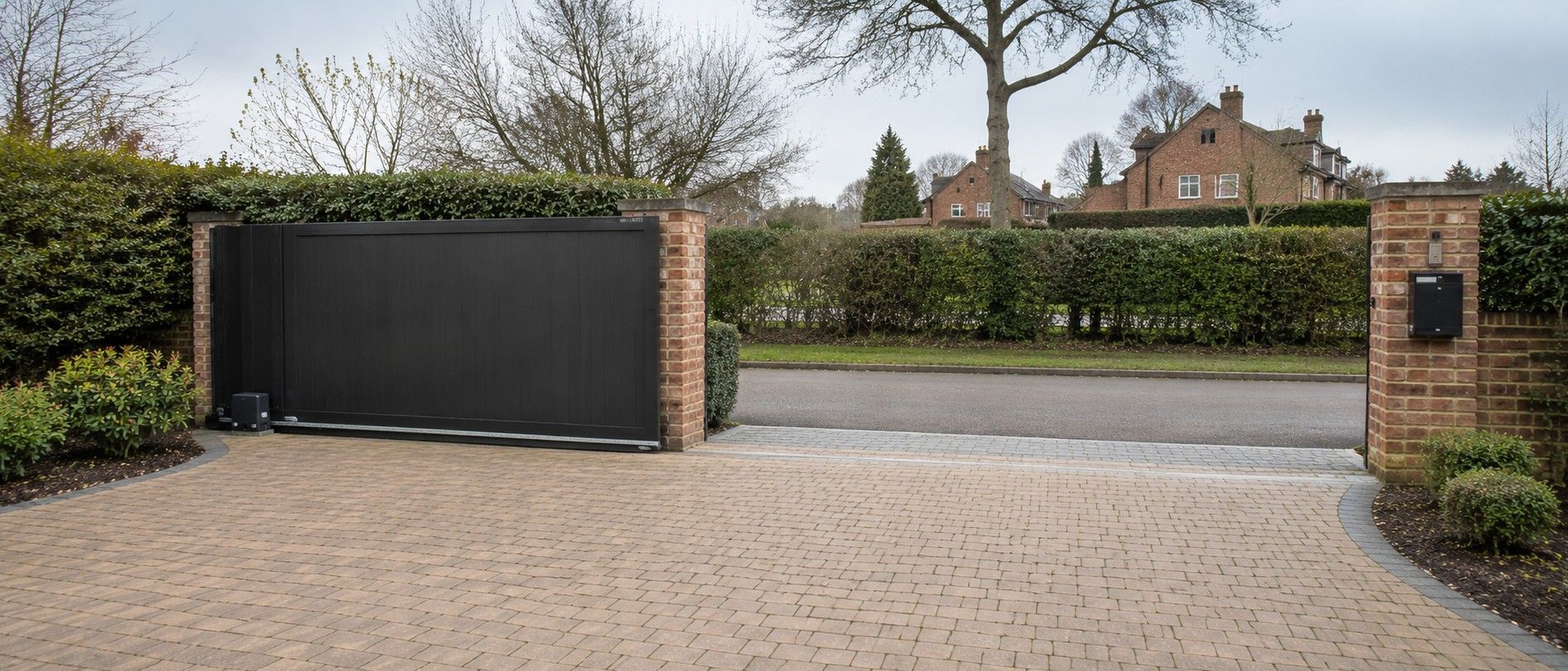 Electric sliding gate fully open and sitting parallel to the boundary wall at a residential driveway entrance