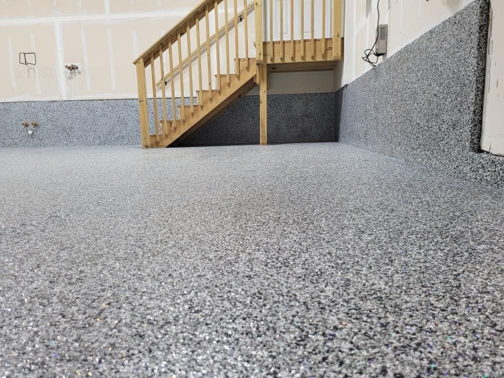 A garage with a staircase and a gray floor.