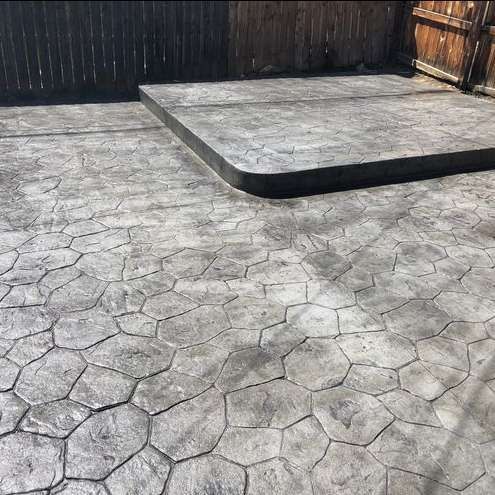 A concrete patio with a wooden fence in the background.