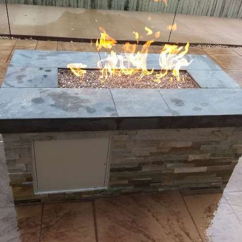 A fire pit is sitting on a tiled floor with flames coming out of it.
